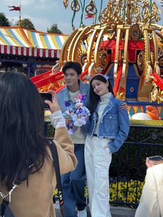 two people are standing in front of a carnival ride and one person is taking a selfie