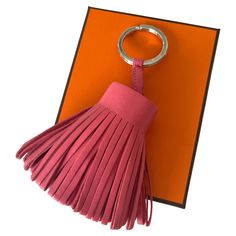 a pink tasselled keychain sitting on top of an orange card holder