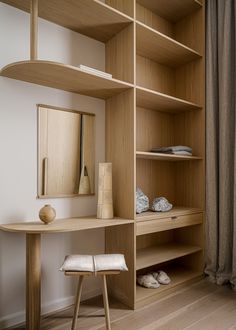 a wooden shelf with a mirror and stool next to it in a room that has wood flooring