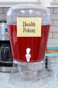 a red and clear container with a label on it that says health potion in front of a blender