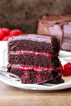 a slice of chocolate cake with raspberry filling on a plate next to a fork