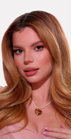 a woman with long blonde hair wearing a necklace and pink dress is posing for the camera