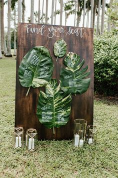 a wooden sign that has some plants on it and candles in front of it with the words find your seat