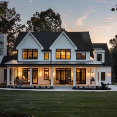 a large white house with lots of windows on the front and side of it at dusk