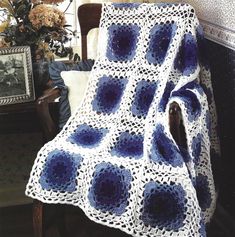 a blue and white crocheted afghan sitting on top of a chair next to a table