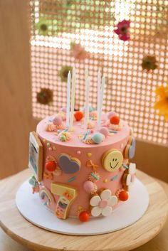 a pink birthday cake sitting on top of a wooden table