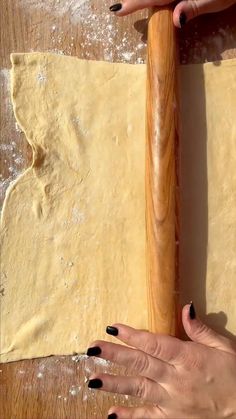 two hands on a table with dough and rolling pin