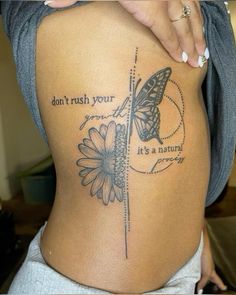 a woman's back with a butterfly and flower tattoo on the side of her stomach