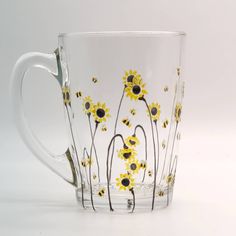 a glass mug with yellow flowers painted on it