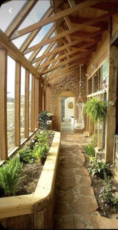 the inside of a house with lots of windows and plants on the side walk way