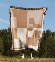 a person standing under a large blanket in the grass