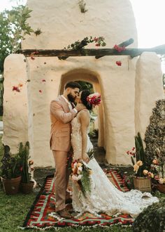 a bride and groom are kissing in front of an archway with succulents