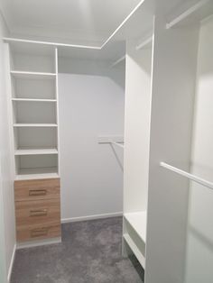 an empty walk - in closet with white walls and shelves, carpeted flooring