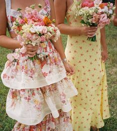 two women standing next to each other in dresses with flowers on the bottom tiers