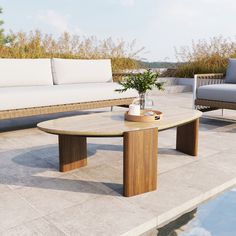 a wooden table sitting on top of a patio next to a couch and coffee table