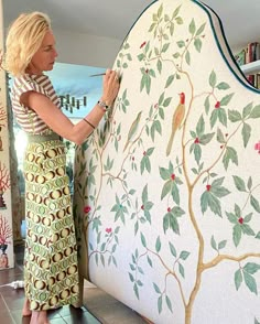 a woman is painting a tree on the wall