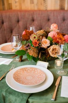 the table is set with plates, silverware and floral centerpieces on it