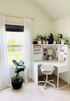 a white desk sitting in front of a window next to a green potted plant