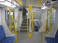 the inside of a bus with blue seats and yellow railings on it's sides