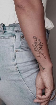 a woman's arm with a small flower tattoo on the left side of her body