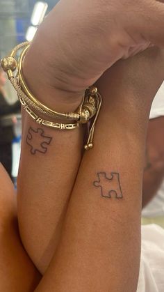 two people with matching tattoos on their legs, one is holding the other's arm