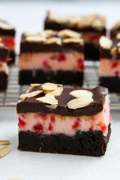 several pieces of dessert sitting on top of a cooling rack with almonds and raspberries