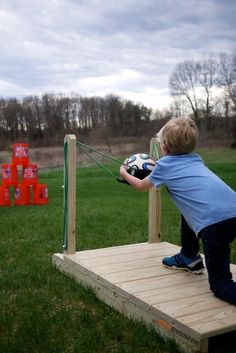 a young boy is playing with a soccer ball on a wooden platform in the grass