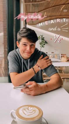 a man sitting at a table with a cappuccino in front of him