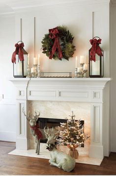 a fireplace decorated for christmas with candles, wreaths and deer figurines on the mantel