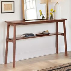 a wooden table with a mirror on top of it next to a lamp and vase