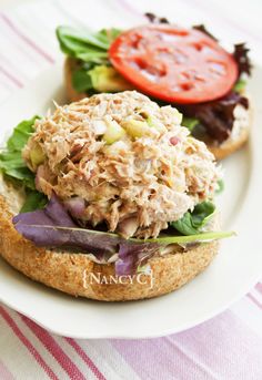 two sandwiches with meat, lettuce and tomato on them sitting on a white plate