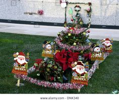 a decorated christmas tree in the grass with santa's helper signs on it