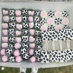 a table topped with lots of cupcakes covered in pink and black frosting