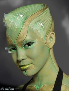 a woman's face with green makeup and gold accents on her body, as if she is from the movie star trek