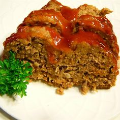 a piece of meatloaf with sauce and parsley on a white dinner plate