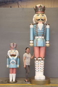 a woman standing next to a giant nutcracker statue