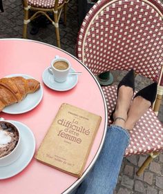 a person is sitting at a table with coffee and croissants on it