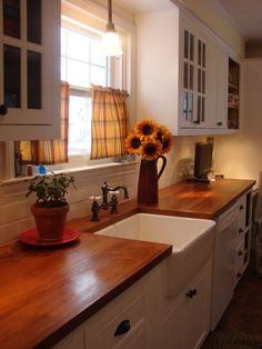 a kitchen with sunflowers in a vase on the counter top and white cabinets