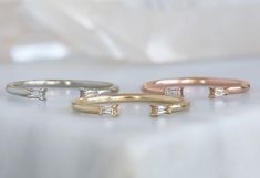 three different colored gold and silver rings on a white tablecloth, with one diamond set in the middle