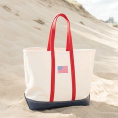 Introducing our stylish and sturdy medium-sized USA Flag Tote, perfect for any occasion. This versatile bag features a classic design with a patriotic touch, adorned with a vibrant American flag patch that proudly showcases your pride. Crafted from high-quality #6 duck canvas, this tote bag is built to last. The durable navy blue vinyl bottom provides extra strength and protection, ensuring that your bag stays in great shape even with daily use. The 10" red cotton webbing handles are not only st Navy Tote Bag, American Flag Patch, Flag Patches, Duck Canvas, Blue Vinyl