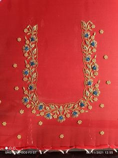 an embroidered red cloth with gold and blue flowers on it, in the shape of a letter u