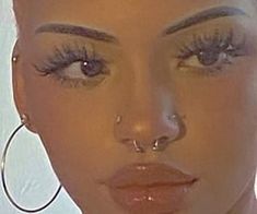 a close up of a woman with large hoop earrings on her head and wearing fake eyelashes