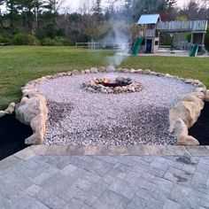 an outdoor fire pit surrounded by rocks and gravel