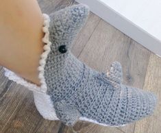 a close up of a person's foot with a knitted shark slipper