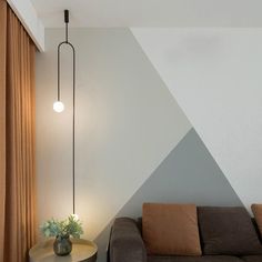 a living room with a couch, table and lamp next to a wall that has a triangle design on it