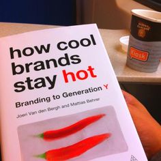 the book how cool brands stay hot is held in front of a coffee cup