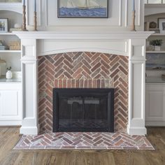 a brick fireplace in a living room with white shelves and a painting on the wall