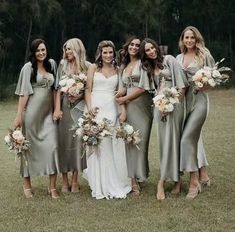 a group of women standing next to each other wearing dresses and holding bouquets in their hands