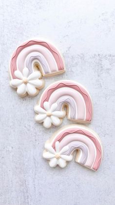 two cookies decorated with pink and white icing on top of a table next to each other