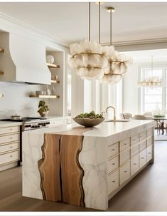 a large white kitchen with marble counter tops and wooden cabinetry in the center island